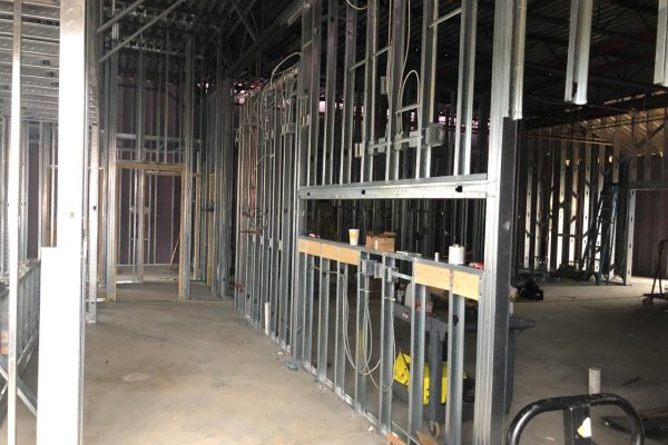 Interior view of structural steel framing and metal stud installation during building construction