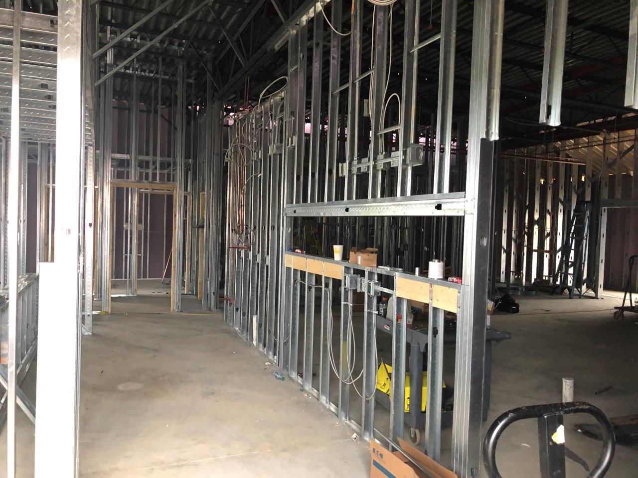 Interior view of structural steel framing and metal stud installation during building construction