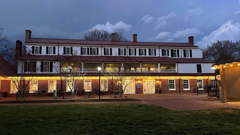 Hanover Tavern illuminated in the evening with outdoor gathering spaces.