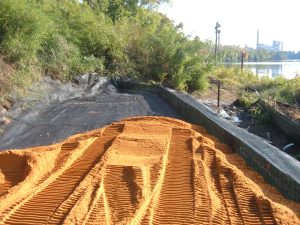 Slope stabilization system under construction using geosynthetic reinforcement to protect a riverbank from erosion.